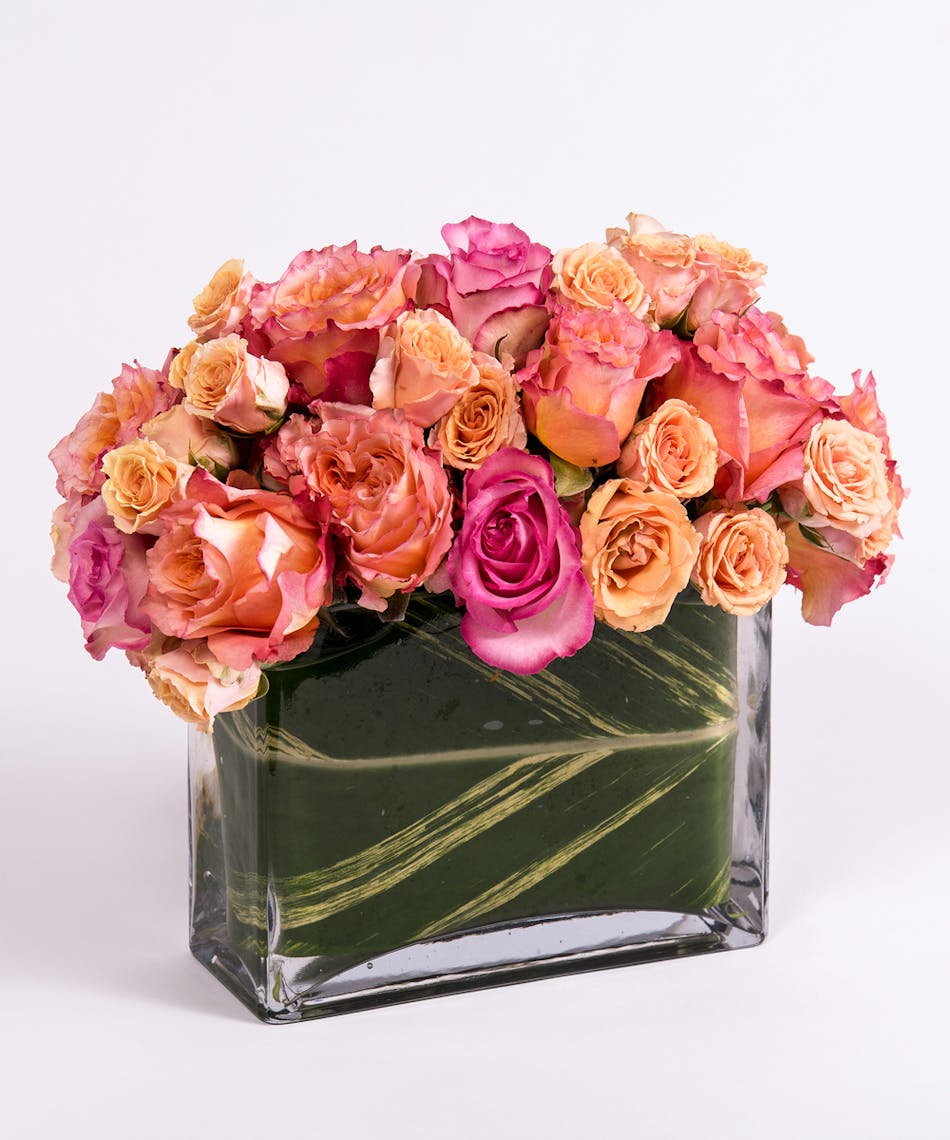 pink, peach and orange roses in a rectangular glass vase