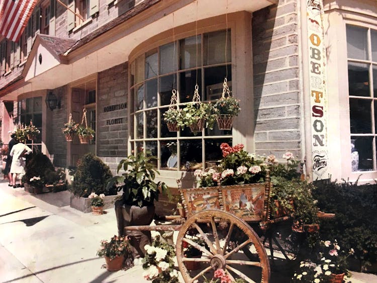 A wooden cart holds potted plants in this 1950s look at the exterior of our downtown location